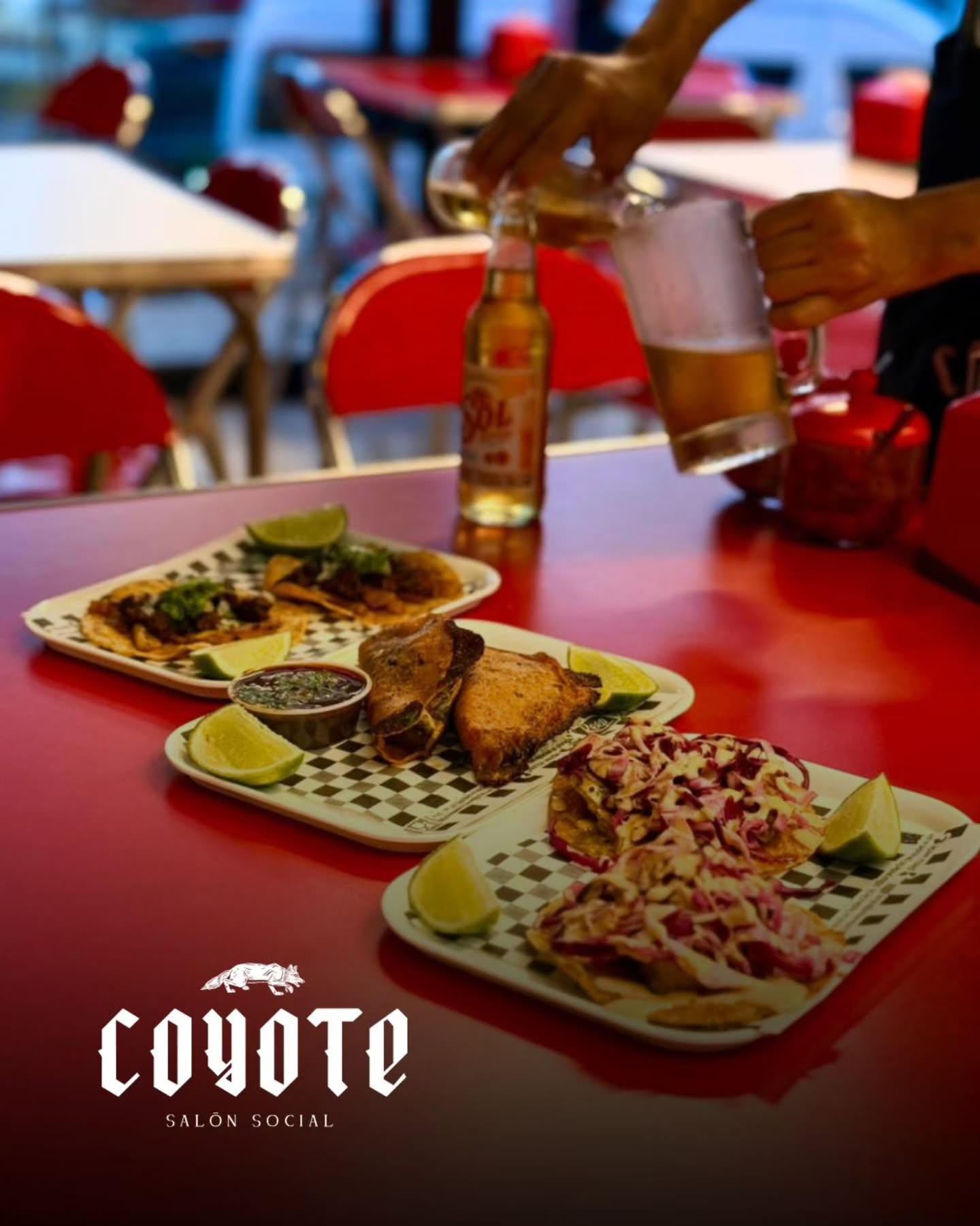 Tacos y cerveza sirviéndose sobre la mesa roja de Coyote